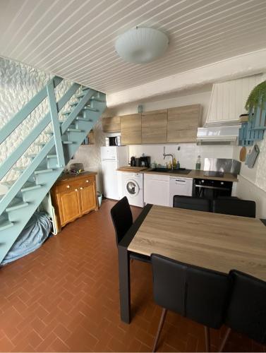 une cuisine avec une table à manger et un escalier dans l'établissement la Palmette , NOUVEAU ! climatisée et wifi, à Lapalme
