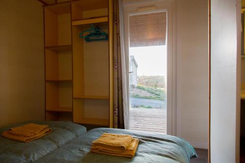a room with a bed and a window with towels at LES CHALETS D HERMINE in Montredon-Labessonnié