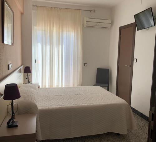 a hotel room with a bed and a window at Hostal Internacional in Miami Platja