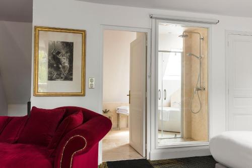 a living room with a red couch and a shower at Hostellerie Du Château Les Muids in La Ferté-Saint-Aubin