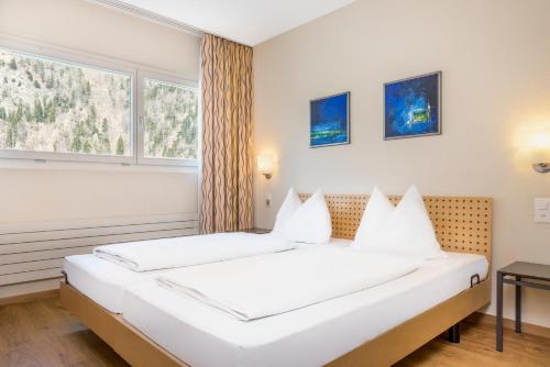 a hotel room with a bed, chair, lamp and window at Hapimag Ferienwohnungen Interlaken in Interlaken