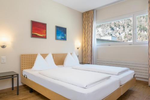 2 camas en una habitación con ventana en Hapimag Ferienwohnungen Interlaken, en Interlaken