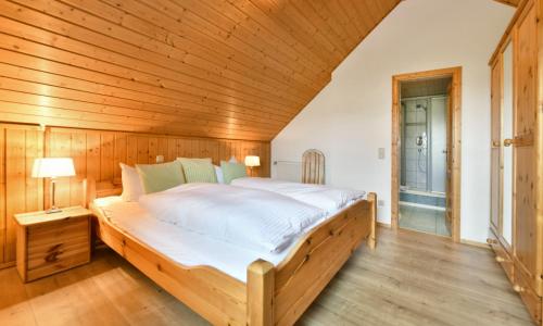 Cama grande en habitación con techo de madera en Oberlützenbachshof, en Geisa