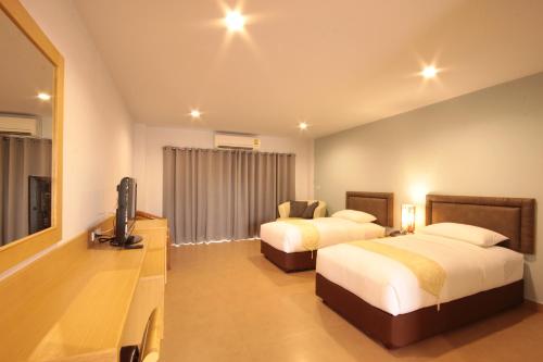 a hotel room with two beds and a flat screen tv at Paragon Suites Resort in Jomtien Beach