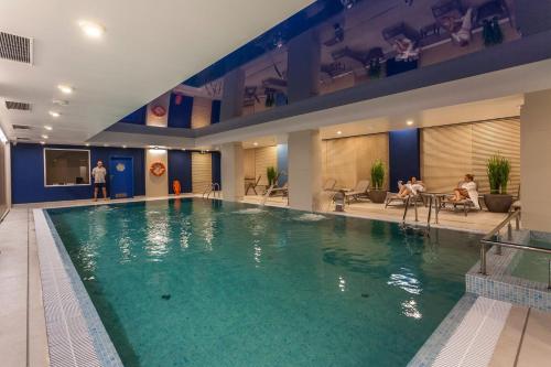 a large swimming pool in a hotel with people sitting on chairs at Stare Miasto Gdansk Jaglana - Comfy Apartments in Gdańsk