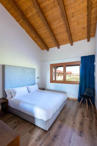 a bedroom with a large white bed and a window at LAS RIBERAS. APARTAMENTOS RURALES in Oviñana