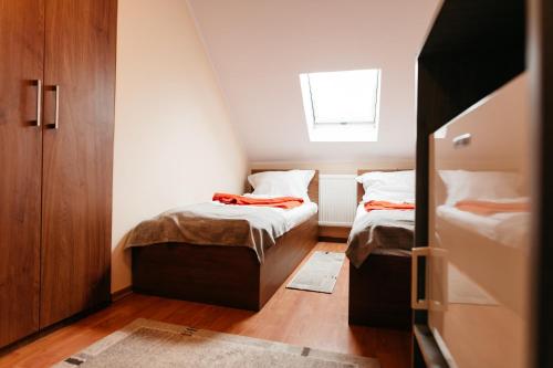 Habitación pequeña con 2 camas y ventana en Pension Rose-Trandafirul, en Borsec