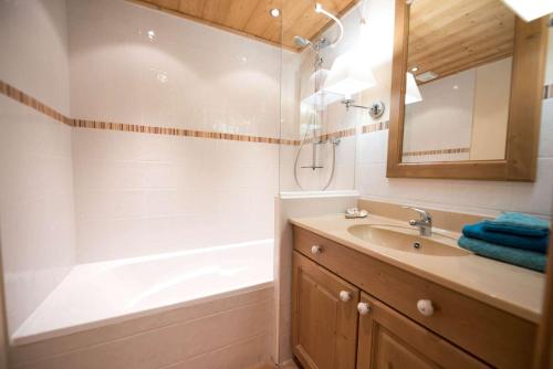 uma casa de banho com uma banheira, um lavatório e um espelho. em La Carte Postale em Duingt