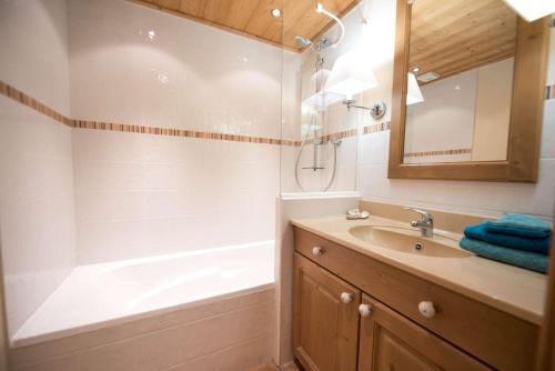 Un baño con bañera, lavabo y espejo. en La Carte Postale, en Duingt