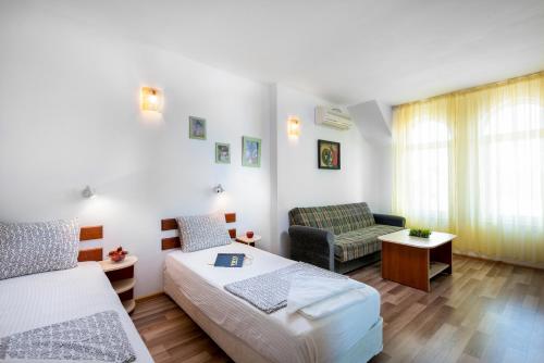 a bedroom with two beds and a couch and a chair at Guest House Zara in Primorsko