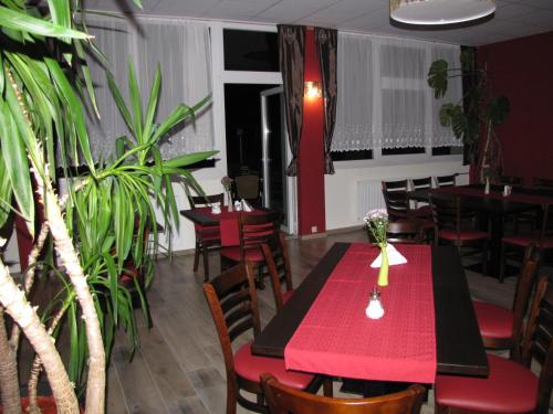 a restaurant with red tables and chairs and plants at Hotel Stadt Wittstock in Wittstock