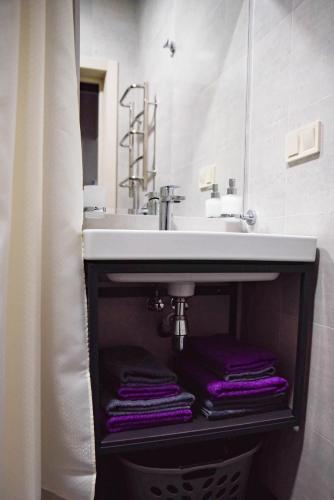 a bathroom with a sink with purple towels under it at Corner House in Odesa