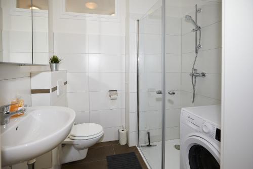 ein Badezimmer mit einem WC, einem Waschbecken und einer Waschmaschine in der Unterkunft Helle und gemütliche Wohnung in zentraler Lage in Graz