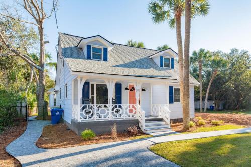 ein weißes Haus mit einer Veranda und Palmen in der Unterkunft Folly Vacation Beautiful Beach Cottage 209-A in Folly Beach