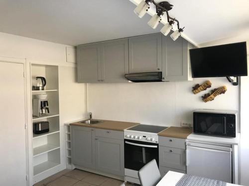 a kitchen with white cabinets and a stove and a microwave at Hyacint Studio in De Haan