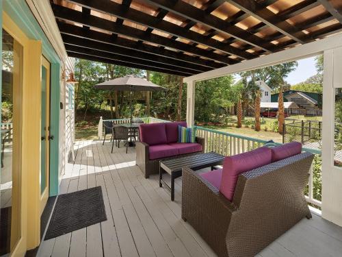 - une terrasse couverte avec des chaises, une table et un parasol dans l'établissement Folly Vacation 305 E Erie Fantastic Location, à Folly Beach