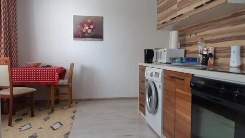 a kitchen with a washing machine and a table at Szoba konyha lakas in Komárno