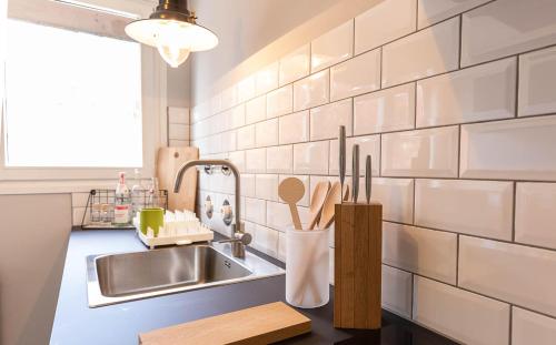 una cocina con fregadero de acero inoxidable y baldosas blancas de metro en WÄLDER: Quartier Titisee en Titisee-Neustadt