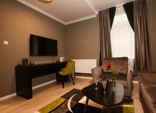 a living room with a couch and a desk with a television at Resita Residence Sauna Apartment in Reşiţa