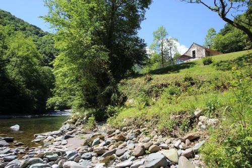 a river with rocks and a house on a hill at Monyoya ,site exceptionnel au coeur des Pyrénées in Sarrance