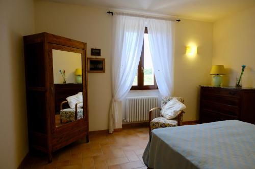 sypialnia z lustrem, łóżkiem i krzesłem w obiekcie Agriturismo Vigna Sul Lago w mieście Montefiascone