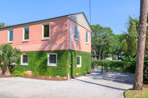 a building covered in green ivy next to a palm tree at Folly Vacation 114B Townhouse, perfect family vacation, pets welcome! in Folly Beach