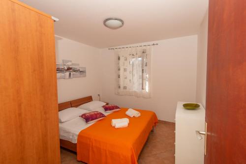 a small bedroom with a bed with an orange blanket at Melada in Molat