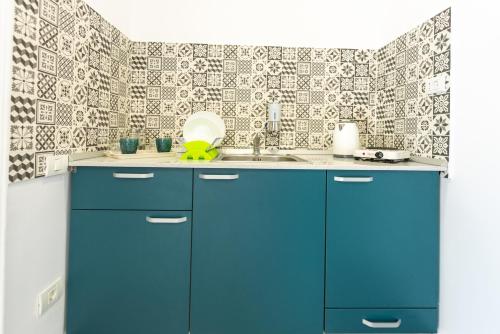 a kitchen with blue cabinets and a sink at Vila Jun in Eforie Nord