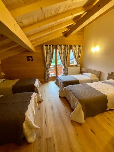 - une chambre avec 3 lits dans une pièce dotée de plafonds en bois dans l'établissement Chalet luxe L'HIBISCUS, à Samoëns