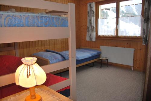 a bedroom with two bunk beds and a table with a lamp at Ferienwohnung Bürchen in Bürchen