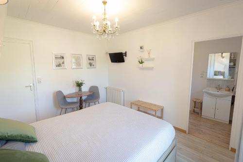a white bedroom with a bed and a sink at Les 4 saisons in Graye-sur-Mer