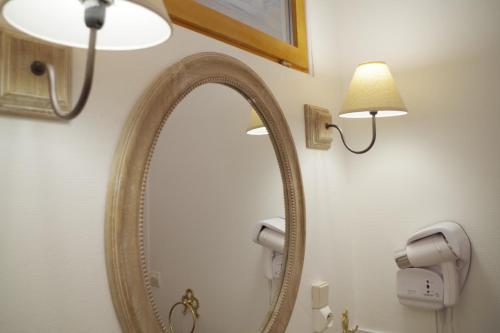 a mirror in a bathroom with a light and a lamp at Les 4 saisons in Graye-sur-Mer