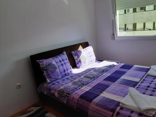 - une chambre avec un lit doté de draps violets et une fenêtre dans l'établissement Apartments Jovana, à Žabljak
