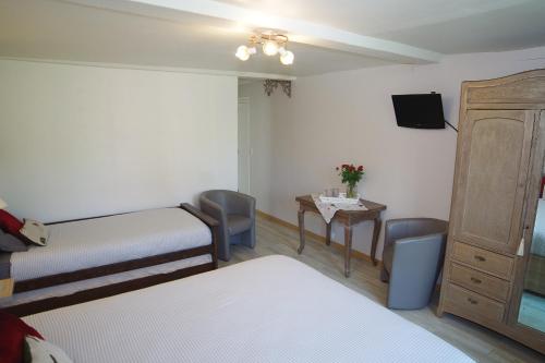 a room with two beds and a table and a tv at Les 4 saisons in Graye-sur-Mer