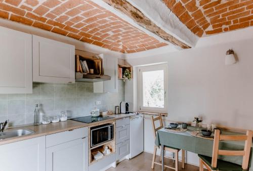 uma cozinha com armários brancos e uma mesa com cadeiras em Lindhouse - Country House a Govone em Govone
