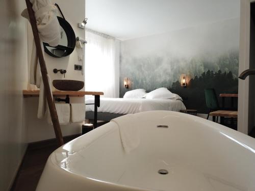 ein Bad mit einer Badewanne und einem Bett in der Unterkunft Hotel Les Glycines in Vieille-Brioude