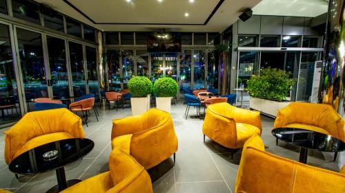 a restaurant with yellow chairs and tables and windows at Hotel Fieri in Fier