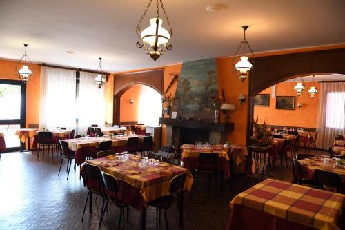 uma sala de jantar com mesas e cadeiras e um lustre em Hotel La Capannina em Massino Visconti