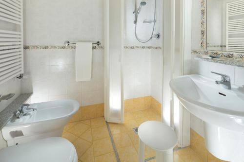 Baño blanco con aseo y lavamanos en Hotel Vanni, en Misano Adriatico