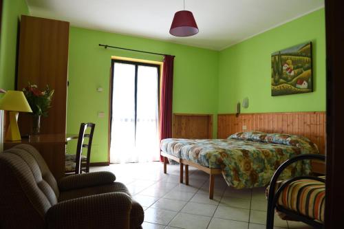 ein Schlafzimmer mit grünen Wänden, einem Bett und einem Tisch in der Unterkunft Hotel La Capannina in Massino Visconti