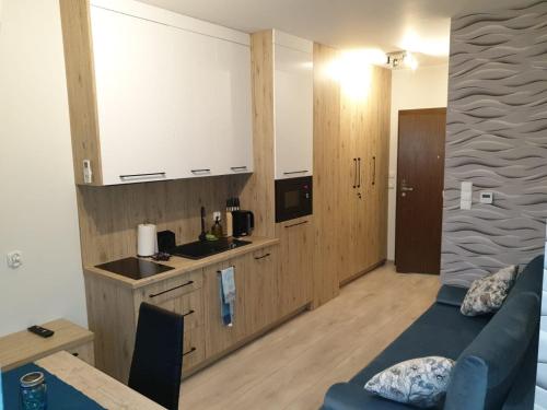 Il comprend un salon avec un canapé bleu et une cuisine. dans l'établissement Apartament u Brydzi Apartt99, à Łeba