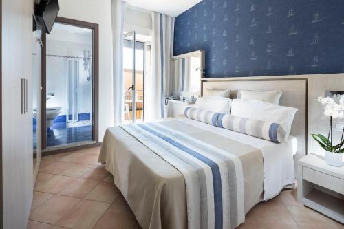 a bedroom with a large bed with a blue wall at Hotel Vanni in Misano Adriatico