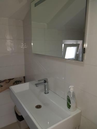 a white bathroom with a sink and a mirror at Apartments and Rooms Vesna Novalja in Novalja