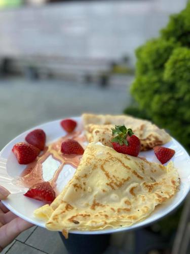 a person holding a plate of food with strawberries on it at Kamienica Morska Gdynia in Gdynia