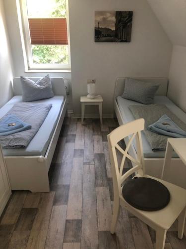 two beds in a room with a chair and a table at Waldperle in Jarmen