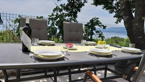 a table with plates and glasses and a bottle of wine at Apartments Turan in Rijeka