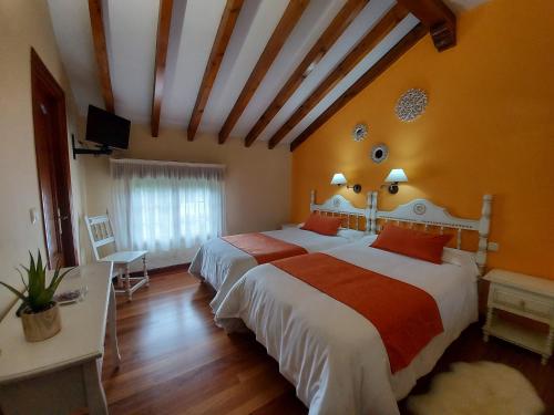 a bedroom with two beds and a television in it at Posada El Jardin in Santillana del Mar