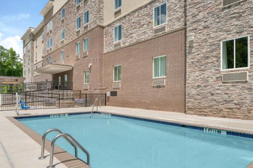 una piscina di fronte a un edificio in mattoni di Candlewood Suites - Newnan - Atlanta SW by IHG a Newnan