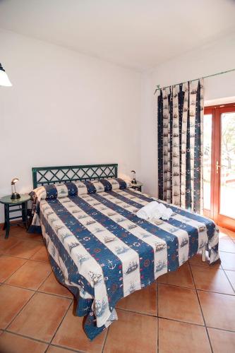 a bedroom with a bed with a blue and white blanket at Stella Marina Budoni in Budoni