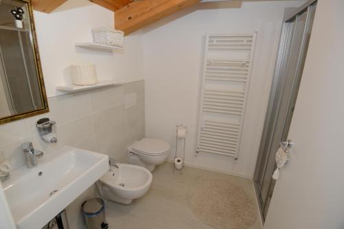 een witte badkamer met een toilet en een wastafel bij Casa di Patrizia in Calavino